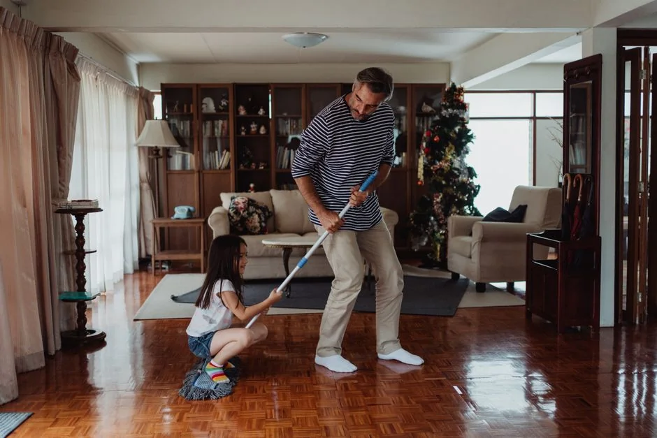 A professional cleaner in protective gear vacuuming the floor in a modern living room.